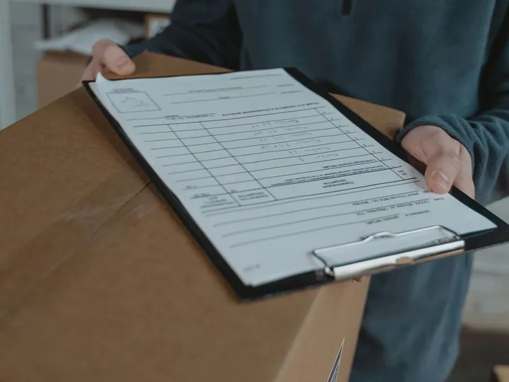 Person holding a shipping checklist over a parcel